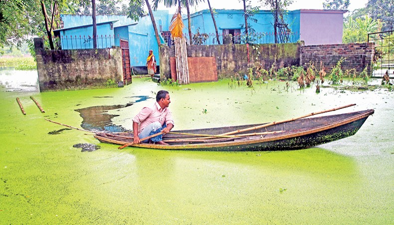 A man comes out of his house by boat in floodwater in Rahman Nagar neighbourhood of Uttar Khan area of the capital on Monday. — Sony Ramany