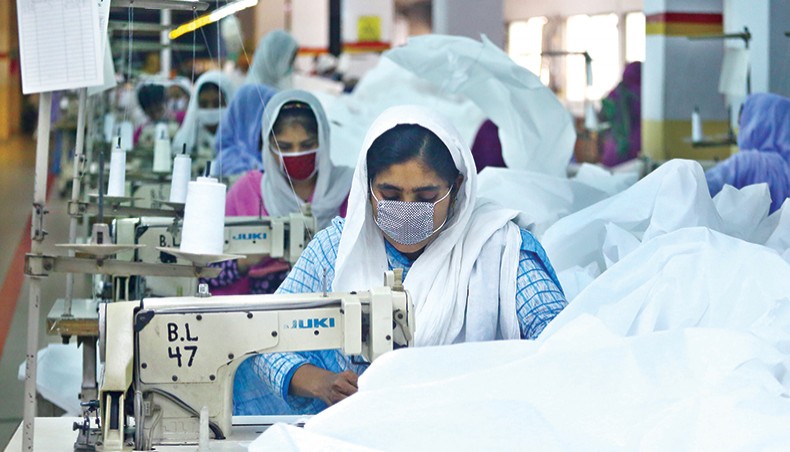 A file photo shows workers making personal protective equipment at a readymade garment factory on the outskirts of Dhaka. The country’s economy grew by 5.24 per cent in the last fiscal year 2019-2020 despite an unprecedented blow to economy in the last quarter of the year by the COVID-19 outbreak, according to the Bangladesh Bureau of Statistics provisional estimates. — New Age photo