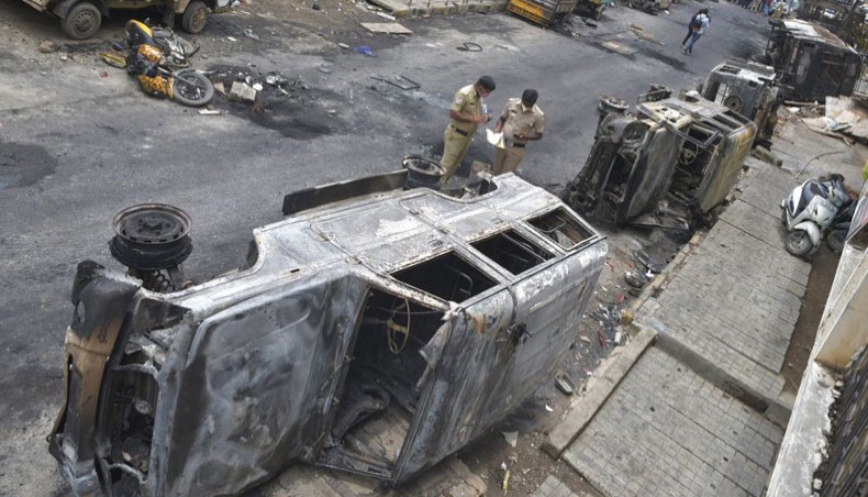 Police officials look at burnt police vehicles along a street in Bangalore on August 12, 2020, after violence broke out overnight in Devara Jevana Halli area following a ‘derogatory’ Facebook post that sparked riots. — AFP