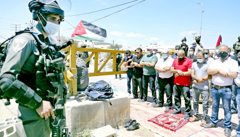 Members of the Israeli security forces stand guard as Palestinian demonstrators perform the Friday prayers during a rally to protest against Israel’s plan to annex parts of the occupied West Bank, in the village of Haris, southwest of Nablus, on Friday. — AFP photo