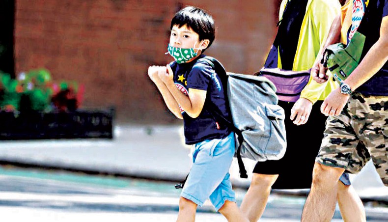A child wears a face mask and a backpack in Kips Bay as the city continues Phase 4 of re-opening following restrictions imposed to slow the spread of coronavirus on August 15 in New York City. — Common Dreams/ Getty Images/Noam Galai