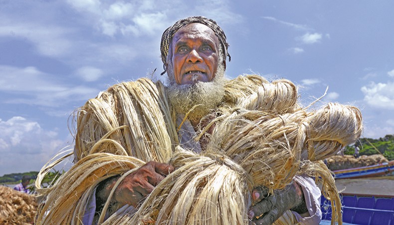 A file photo shows a man carrying jute fibres at a market on the outskirts of Dhaka. — New Age photo