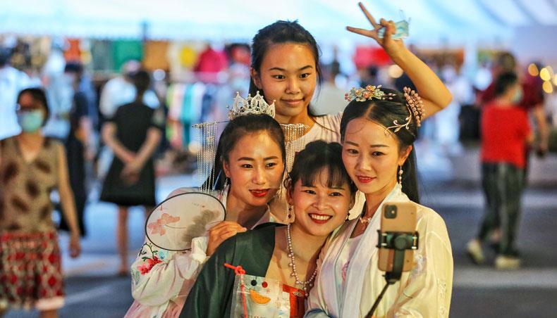 This photo taken on August 27, 2020 shows women wearing traditional clothing posing for photos as they visit a night market in Wuhan in China’s central Hubei province. — AFP photo