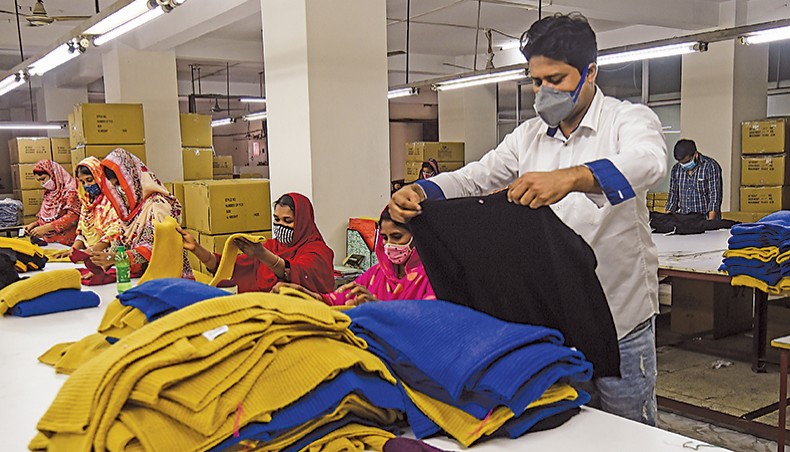 This photograph taken on June 18, 2020 shows an official inspecting a sweater while labourers work at a garment factory in Savar on the outskirts of Dhaka. Most female workers in Bangladesh’s readymade garment sector are concentrated in low paid jobs and the participation of women in managerial positions has not improved in the sector, said a recent report of the International Labour Organisation. — AFP photo