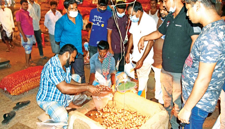 People crowd an onion trader at Karwan Baar in Dhaka on Tuesday after a sharp increase in onion prices. — New Age