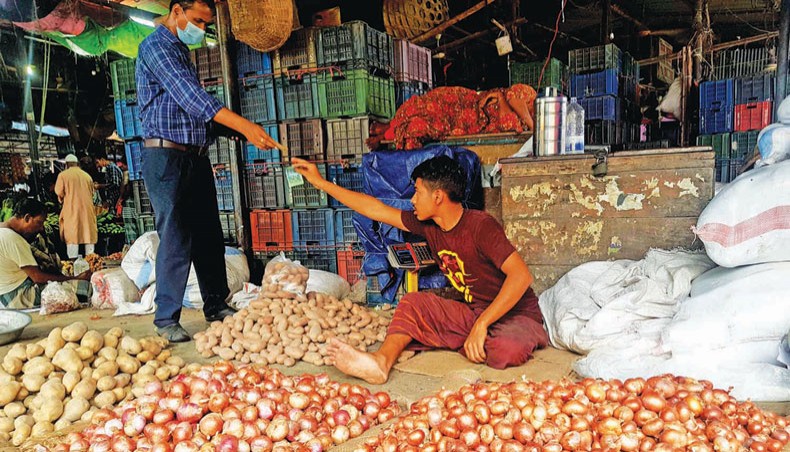 A vendor sells different commodities, including onion, at the Karwan bazar kitchen market in Dhaka on Monday. — New Age photo