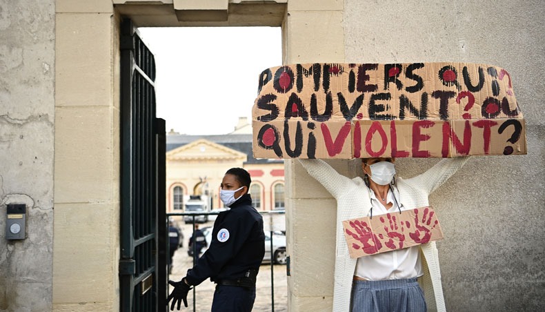 A member of women’s rights association holds a placard reading ‘Firefighters who save? or rape?’ past a policewoman during a protest prior to the start of a hearing following the referral of a case of rape of a minor by three fire-fighters at the investigating chamber outside the appeal chamber at Versailles, on September 24, 2020. — AFP photo