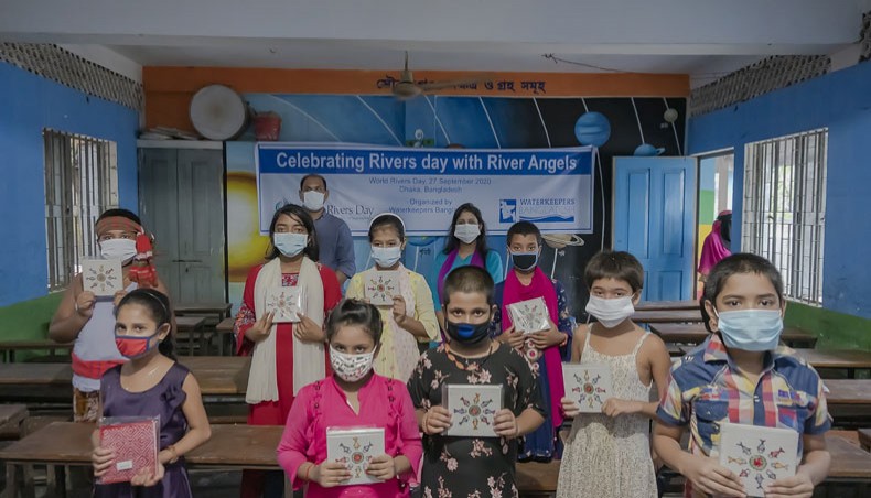 Children at a government primary school in Gazipur pose for a photo session with educational tools at a programme jointly hosted by Waterkeepers Bangladesh and River Angle in observance of World River Day on Sunday. — New Age Photo