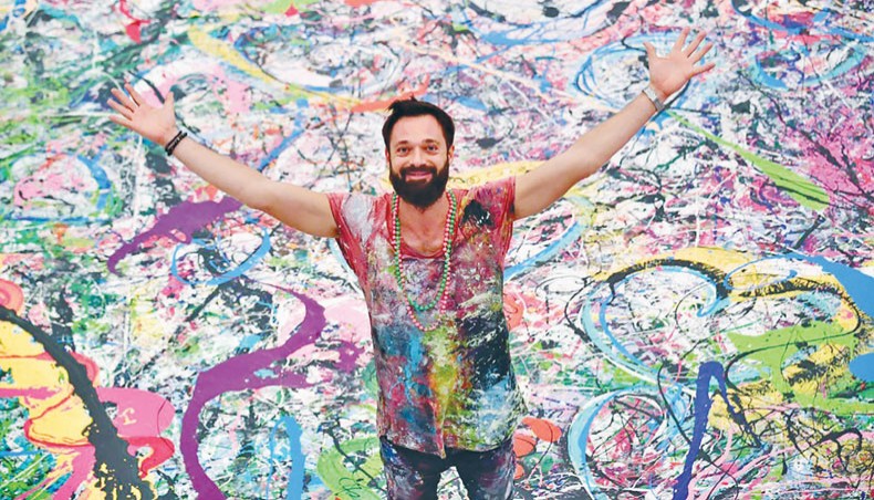Contemporary British artist Sacha Jafri gestures as he stands on his record-breaking painting entitled ‘The Journey of Humanity’ recently, in the Emirati city of Dubai. — AFP photo