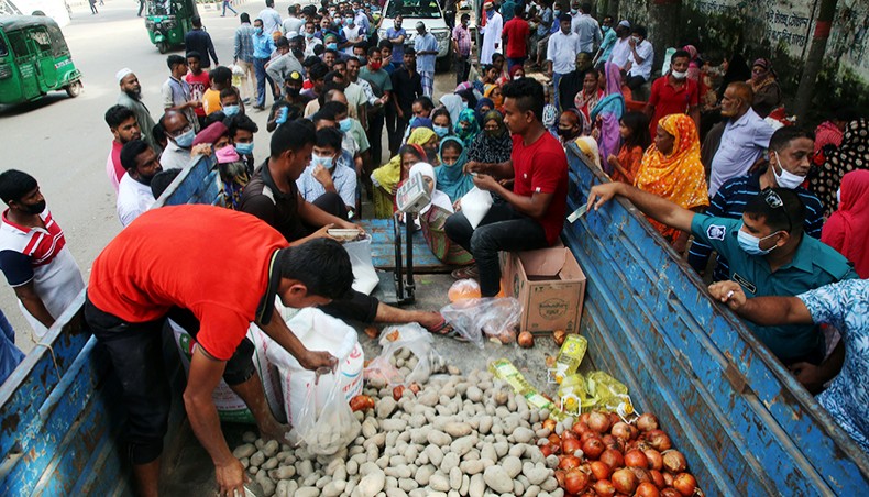 People wait in queues on a road near the National Press Club in Dhaka on Wednesday to buy potato, onion and other products from a TCB outlet amid soaring prices of daily commodities. — Sony Ramany