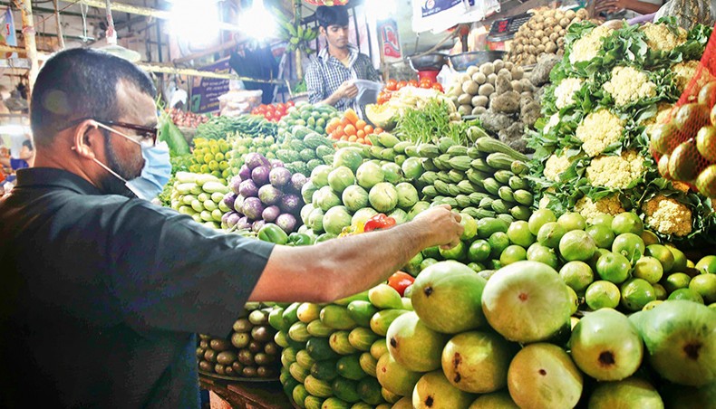 A man buys vegetables at a shop at a kitchen market at Plassey in the capital on Friday. The prices of daily essential commodities, including vegetables, remained high on the kitchen markets in the capital, Dhaka, over the week ending on Friday. — New Age photo