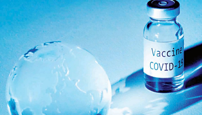 An illustration picture taken on November 19 shows a vial with COVID-19 vaccine sticker and an earth globe. — Agence France-Presse/Joel Saget
