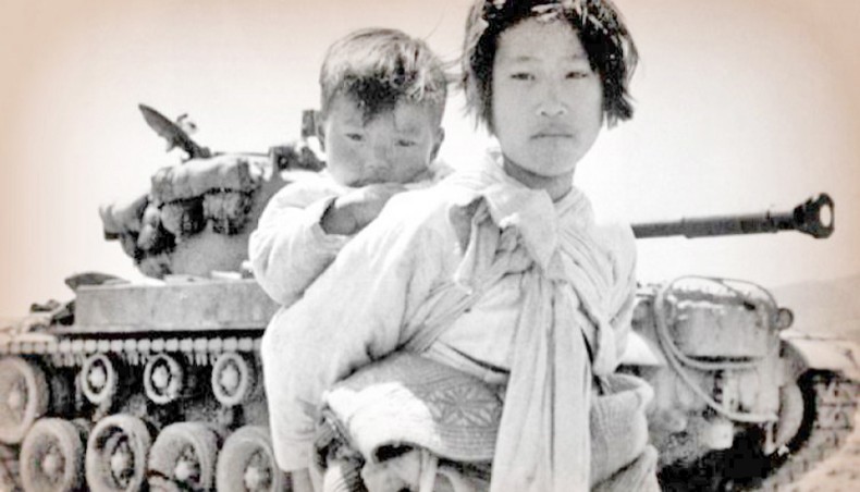 With her brother on her back a war-weary Korean girl passes a stalled M-26 tank in Haengju, Korea on June 9, 1951. — Consortium News/US army/Major RV Spencer