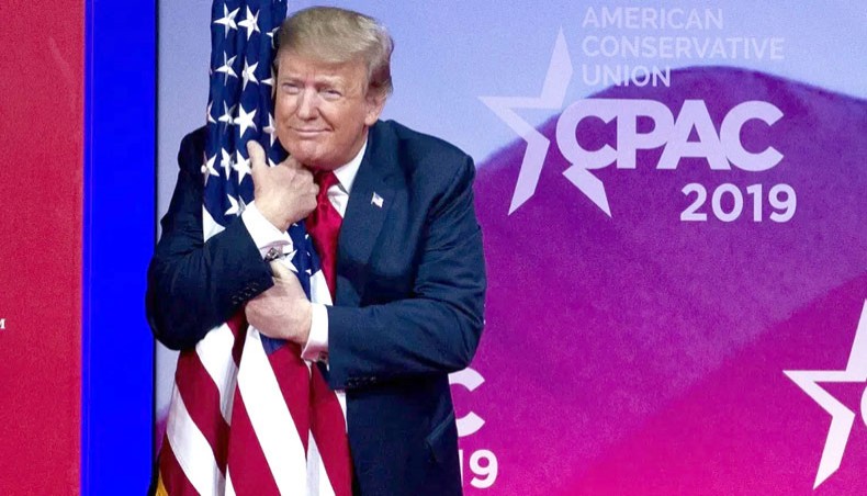 President Donald Trump hugs the American flag before his speech at the CPAC meeting. — The Associated Press/Jose Luis Magana