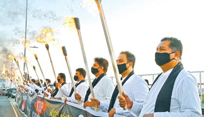 Sri Lanka’s main opposition legislators wearing black masks and black scarves hold torches during protest outside president Gotabaya Rajapaksa’s office in Colombo December 7. — Agence France-Presse/Lakruwan Wanniarachchi