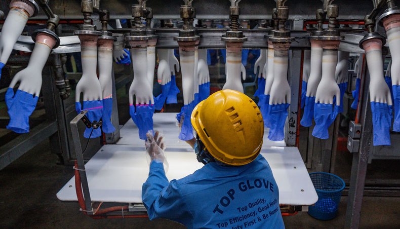 In this file photo taken on August 26, 2020, a worker inspects disposable gloves at the Top Glove factory production line in Shah Alam on the outskirts of Kuala Lumpur. — AFP photo