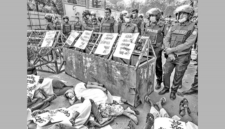 Police prevent protesting injured garment workers of Tazreen Fashions from placing their demands to the prime minister. Stencil artwork of father of the Nation Bangabandhu Sheikh Mujibur Rahman in hoarding in background. November 24, 2020. Dhaka. Bangladesh. — Shahidul Alam/Drik/Majority World.