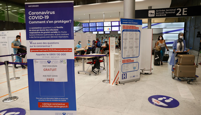 In this file photo taken on July 24, 2020, passengers wearing a face mask arrive in the arrival hall of Roissy-Charles de Gaulle Airport, north of Paris, as a sign for a free COVID-19 test is displayed. — AFP photo
