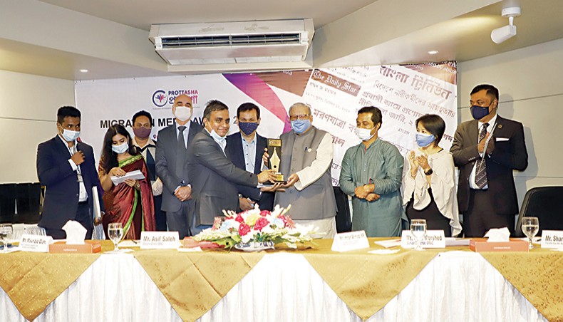 Md Owasim Uddin Bhuyan receives first prize from expatriates’ welfare and overseas employment minister Imran Ahmad at the BRAC Centre Inn in Dhaka on Thursday during the Migration Media Award distribution ceremony for his report published in New Age. — New Age photo