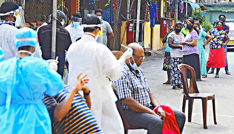 Medical workers wearing protective gear collect swab samples from residents to test for the COVID-19 coronavirus in Colombo on December 30. — Agence France-Presse/Ishara S Kodikara