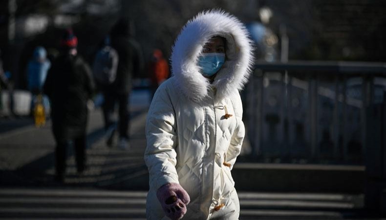 A woman wrapped up from the cold walks along a street on a winter day in Beijing on January 7, 2021, after China's meteorological authority recently issued a severe weather warning across large parts of the country. -- AFP photo