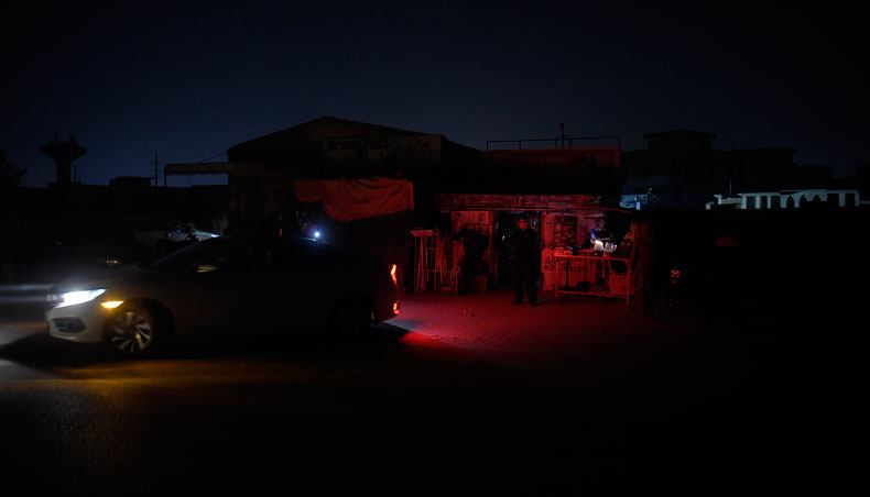 People gather outside shops during an electricity shutdown in Rawalpindi on January 10, 2021, while the restoration efforts were under way after a major power breakdown in the country. — AFP photo