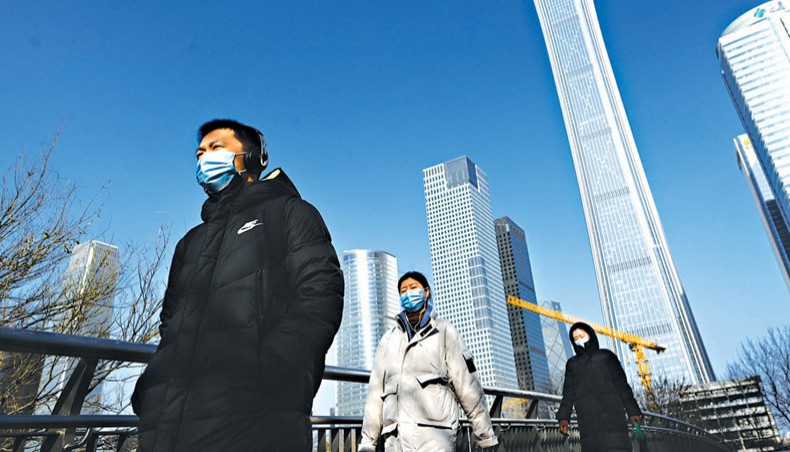 A group of pedestrians walk on an overpass in the central business district in Beijing on January 15, 2021. — AFP photo