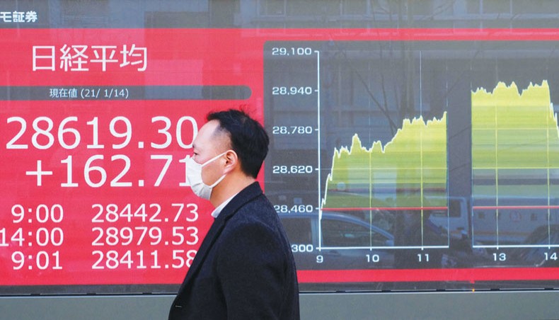 A file photo shows a pedestrian walking past an electronic quotation board displaying share prices on the Tokyo Stock Exchange in Tokyo on January 14. — AFP photo