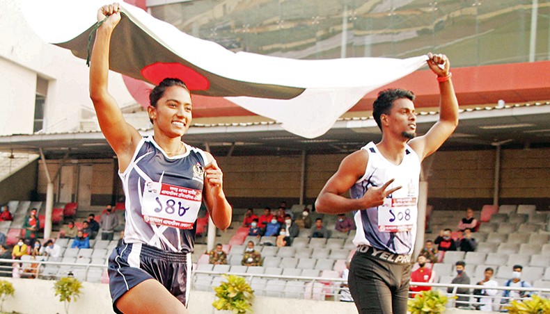 Bangladesh Navy athletes Shirin Akter (L) and Ismail Hossain celebrate with the national flag after winning the women’s and men’s 100-metre sprint title of the 44th National Athletics Championship at the Bangabandhu National Stadium on Friday. — New Age photo