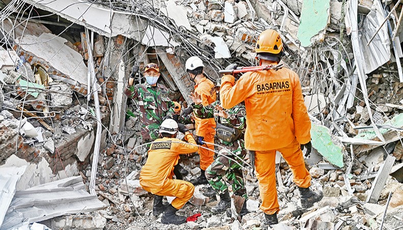 Rescuers try to remove the body on an earthquake victim trapped in a collapsed building in Mamuju on JSaturday a day after a 6.2-magnitude earthquake rocked Indonesia’s Sulawesi island. — AFP photo