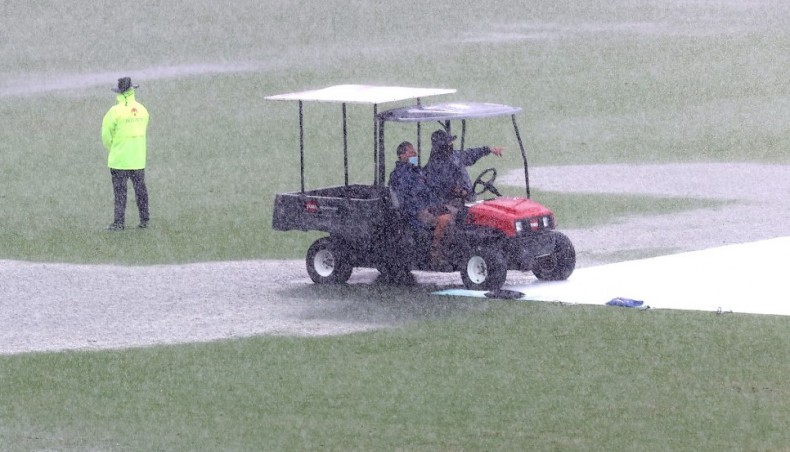 Groundmen monitor after heavy rain stop the play on day two of the fourth Test between Australia and India at the Gabba in Brisbane on Saturday. — AFP photo