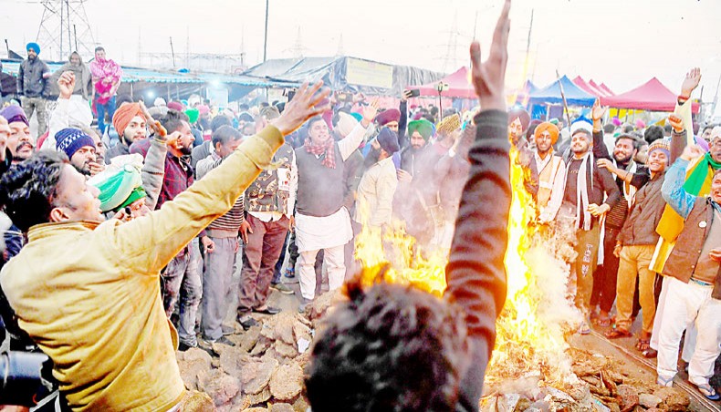 Protesting farmers in India shout slogans while burning copies of recent agricultural reforms bill while celebrating Lohri festival as they continue to protest along a blocked highway against the central government at the Gazipur Delhi-Uttar Pradesh state border in Ghaziabad on January 13. — Agence France-Presse/Prakash Singh