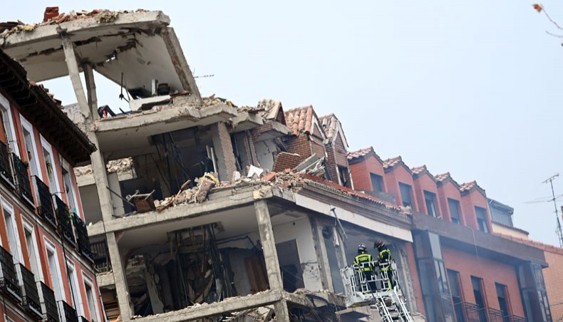 Firefighters on a ladder approach a damaged building in Madrid on January 20, 2021 after a strong explosion rocked it. — AFP