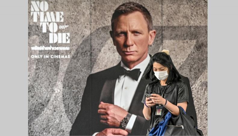 In this file photo taken on February 28, 2020 a woman wearing a facemask amid fears of the spread of the COVID-19 novel coronavirus walks past a poster for the new James Bond movie 'No Time to Die' in Bangkok. -- AFP photo
