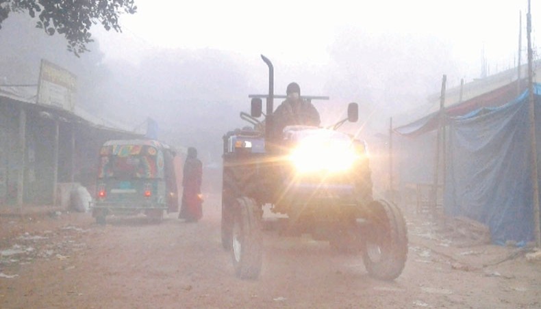 A farmer drives a tractor on a road at Dhunat in Bogura braving a dense fog in the morning amid a low visibility on Friday. — Focus Bangla photo