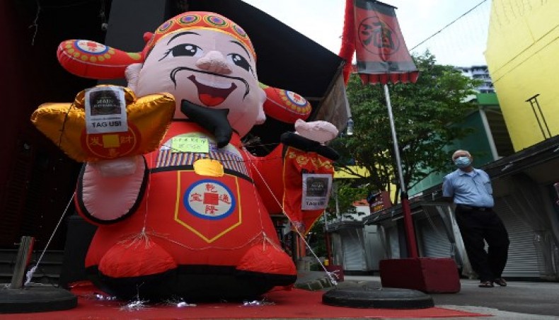 A man walks past an inflatable figurine of the Chinese god of fortune to welcome the Lunar New Year in the Chinatown area of Singapore on January 25, 2021.- AFP photo