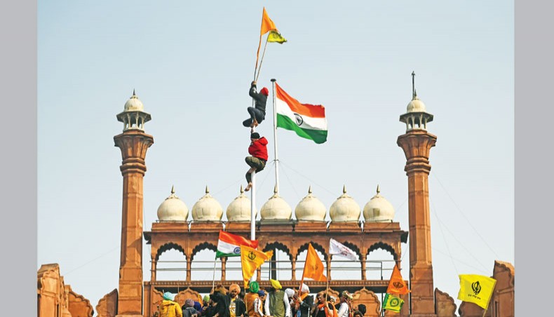 Protesters climb a flagpole at the ramparts of the Red Fort as farmers continue to demonstrate against the central government’s recent agricultural reforms in New Delhi on Tuesday. — AFP photo