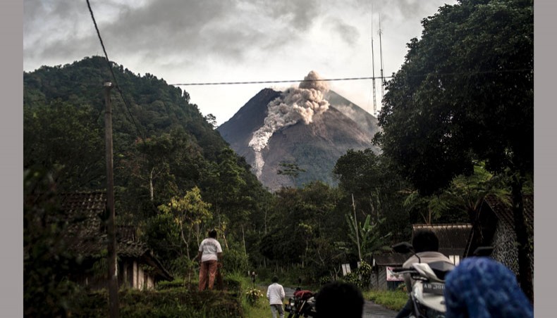 People look up at Mount Merapi, Indonesia's most active volcano, as it spews rocks and ash out for another day in Yogyakarta on January 27. —AFP Photo