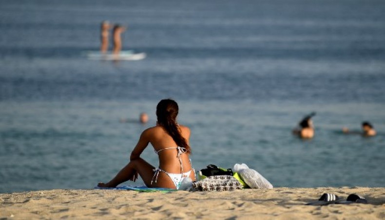 In this file photo taken on July 24, 2020, a woman sunbather sits along a beach as people stand up paddle board in the water in the Gulf emirate of Dubai. In Dubai, known for its luxury haunts and parties, expatriate singles working in the city find the quest for a partner difficult.- AFP photo