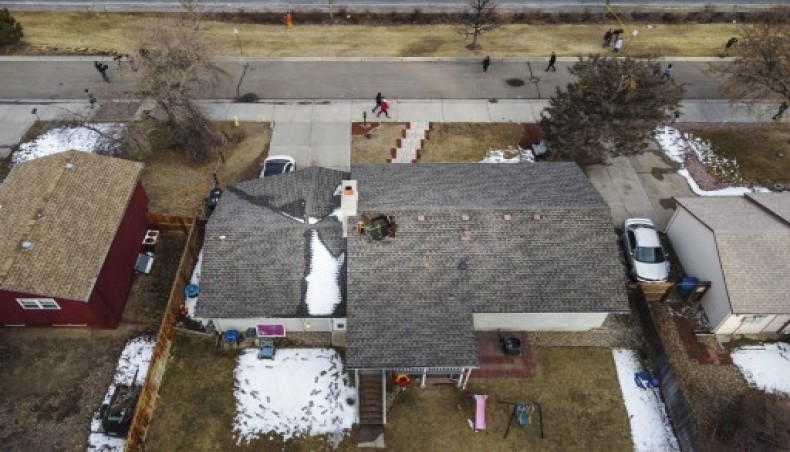 In this aerial view from a drone, people walk past a home with a hole in the roof from falling debris from an airplane engine on February 20, 2021 in Broomfield, Colorado.- AFP photo