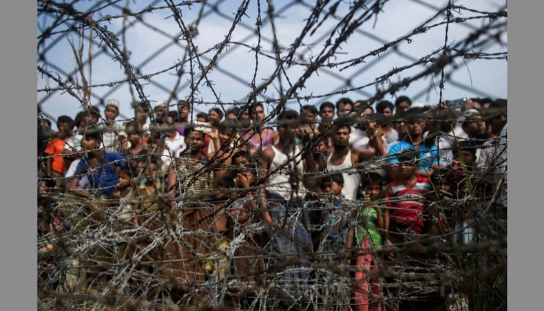 This file photo taken on April 25, 2018 shows Rohingya refugees gather behind a barbed-wire fence at a temporary settlement setup in a ‘no man's land’ border zone between Myanmar and Bangladesh, near Maungdaw district in Myanmar’s Rakhine state. — AFP Photo