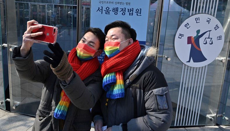 South Korean same-sex couple So Seong-wook and Kim Yong-min take a selfie after a press conference as they file a lawsuit against the National Health Insurance Service for their dependent family status, at the Seoul Administrative Court in Seoul on February 18, 2021. — AFP photo
