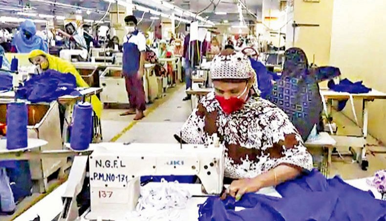 A file photo shows workers wearing facemasks sewing clothes in a garment factory in Dhaka in May. — AFP photo