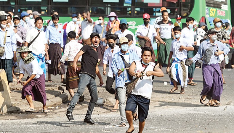 Pro-military supporters carry sling-shots and rocks as they throw projectiles at residents in Yangon on Thursday, following weeks of mass demonstrations against the military coup. — AFP photo