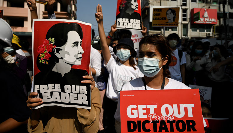 Protesters wearing traditional ‘thanakha’, a yellowish-white cosmetic paste made from ground bark applied on the face, hold placards and flash the three-finger salute during a demonstration against the military coup in Yangon on February 25, 2021. — AFP photo