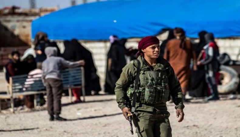 A member of Kurdish internal security stands guard as women await departure during the release of another group of Syrian families from the Kurdish-run al-Hol camp which holds suspected relatives of Islamic State (IS) group fighters, in Hasakeh governorate of northeastern Syria, on February 20, 2021.- AFP photo