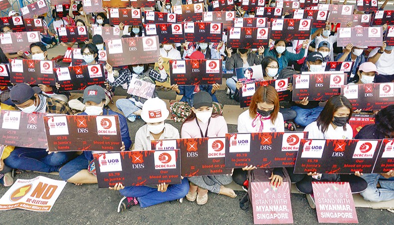 Protesters hold signs during a demonstration against the military coup in Yangon on Friday. — AFP photo