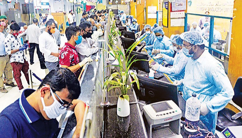 A file photo shows clients queuing up while officials in protective gears giving services at a branch of a private bank in the capital amid the coronavirus outbreak in the country. Thirteen banks faced negative credit growth year-on-year as of December 2020 amid a plunge in demand following the coronavirus outbreak which caused businesses to refrain from taking fresh loans. — New Age photo