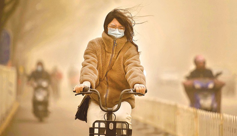 A woman cycles along a street during a sandstorm in Beijing on Monday. — AFP photo