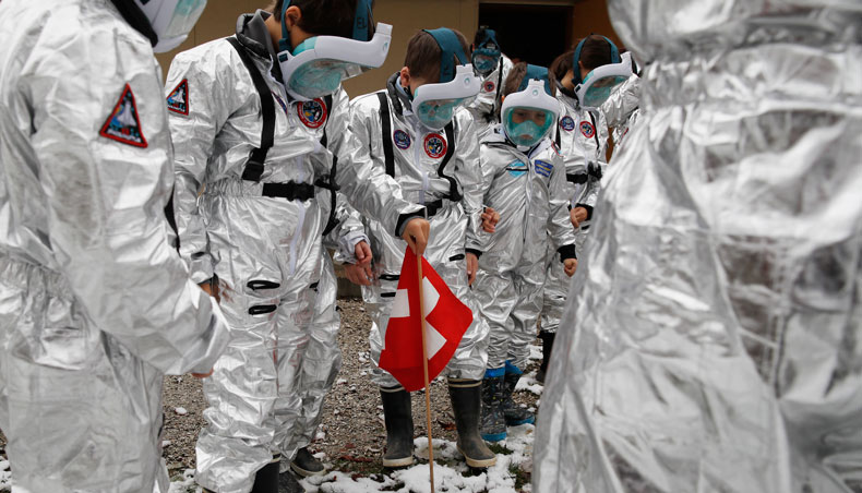 Pupils of the Ecole Vivalys elementary school, wearing spacesuits costumes, plant a Swiss national flag in the ground during their project ‘Mission to Mars’ in Lausanne, on March 17, 2021. — AFP photo